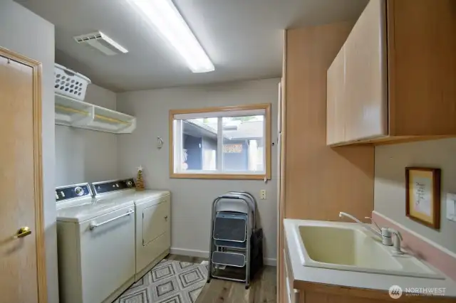 main floor laundry room with utility sink, natural light and built in storage for everyday convenience