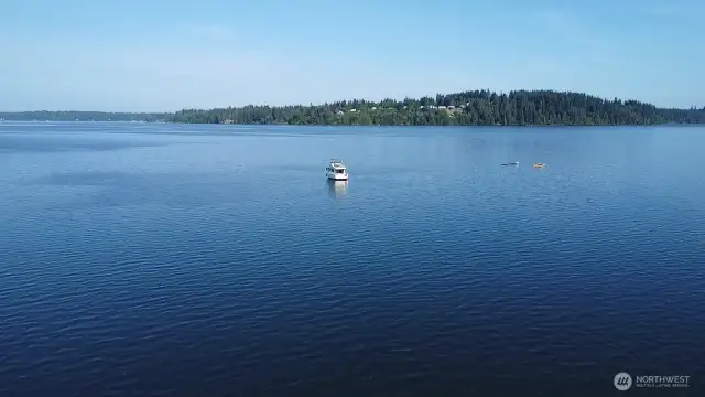 peaceful Totten Inlet views with calm blue waters, moored boat and forested shoreline- nature's beauty in every direction