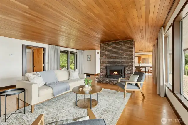 Floor to ceiling windows frame the beautiful views.   Maple floors and wood ceilings in the living room and dining room add warmth and detailing.  Beautiful brick fireplace.