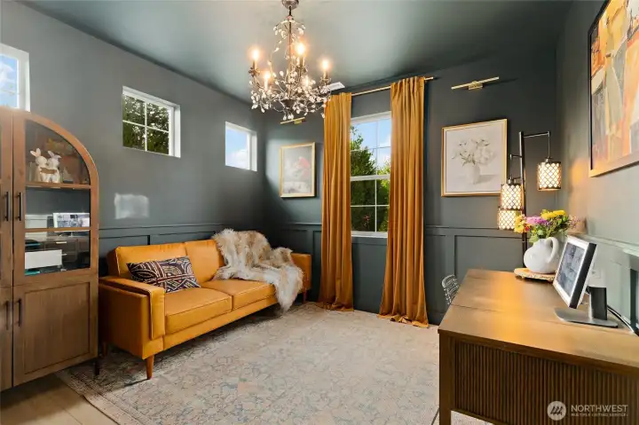 This main-level bedroom is a warm and versatile space, ideal for guests, a home office, or even multi-generational living. Designed with comfort and style in mind, it features rich Studio Green walls and trim (Sherwin-Williams), upgraded wainscoting, and durable LVP flooring. Natural light filters through high-set and standard windows, softened by luxurious drapes. A vintage-inspired chandelier adds just the right amount of charm and character. Conveniently located next to a beautifully remodeled ¾ bathroom, this room offers both privacy and practicality for everyday living or hosting overnight guests.