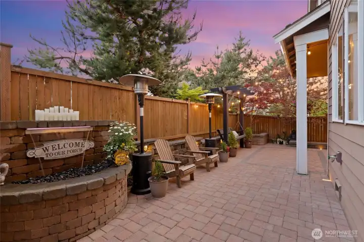 The south facing backyard blends charm, comfort, and convenience. A tranquil water feature sets a calming tone, while built-in lighting and patio heaters—yours to keep—ensure warmth and ambiance throughout the seasons. The Adirondack chairs also stay, creating an inviting space for relaxed conversation or quiet reflection. Surrounded by lush plantings and glowing string lights, this outdoor retreat is ready for you to enjoy from day one.