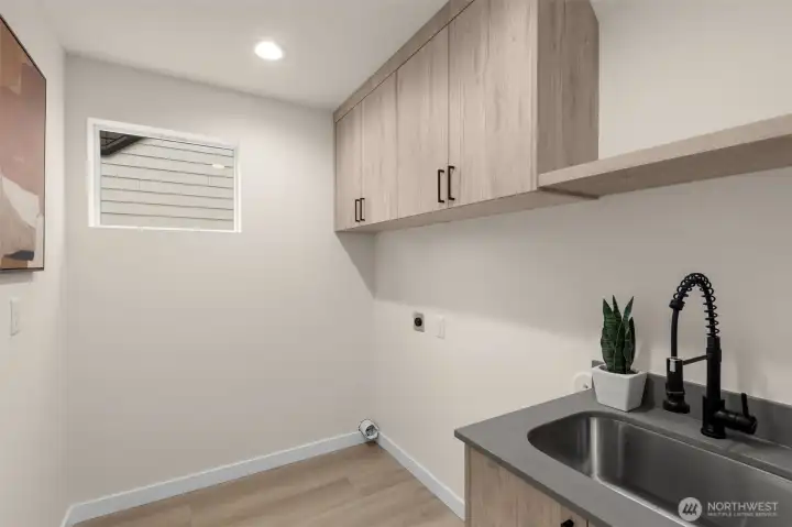 The enlarged laundry room carries a stainless steel sink & built in cabinetry for more storage.