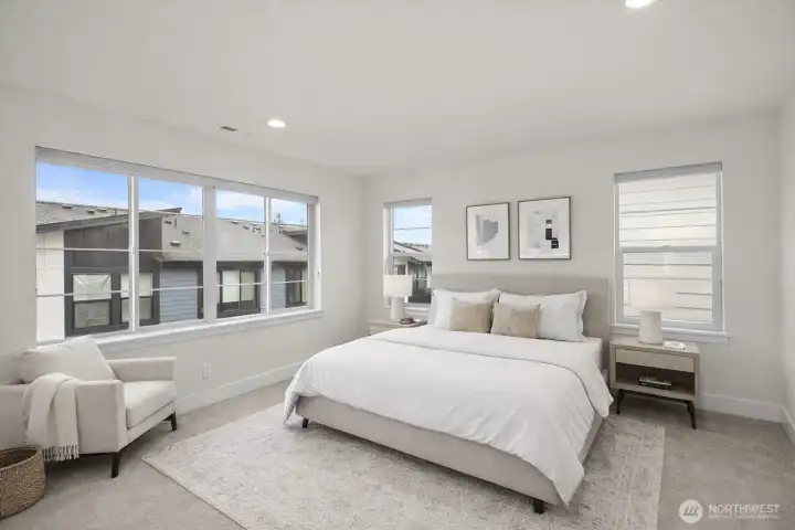 The primary suite is light and inviting, with large windows that fill the space with natural light and an airy feel.