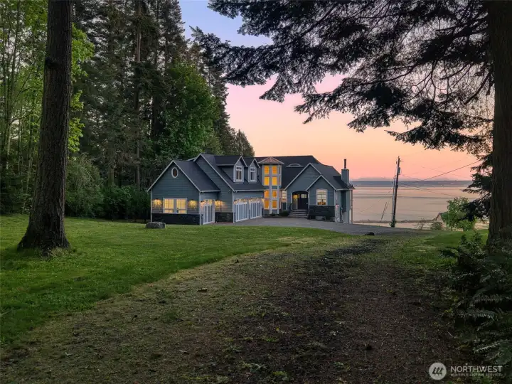 Beyond a gated entry, a tree-lined drive reveals a sunlit lawn that rolls gracefully toward the shoreline, creating a striking sense of arrival & connection to the water.
