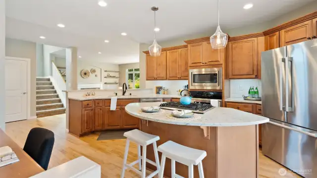 This gorgeous kitchen is the heart of the home - warm, welcoming, and beautifully updated. New quartz countertops bring a sleek, modern touch, while the curved island adds both charm and functionality. Just behind the sink, a second breakfast bar offers the perfect spot for morning coffee, homework time, or happy hour snacks.