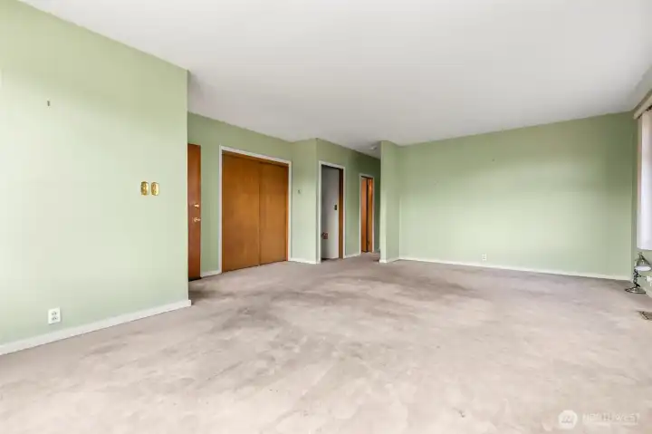 Looking from the large front window to the dining area and beyond to the rear of the unit - first open door is the basement stairway, second open door with the light on is the bathroom