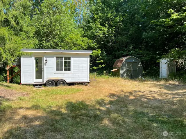 View of tiny home, shed and porta-potty.
