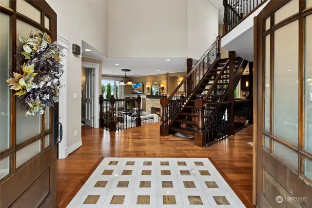 Grand double height entry with dramatic floating wood staircase & designer tile