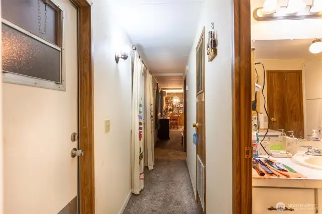 Looking from primary bedroom down the hall towards living room, dining room and kitchen