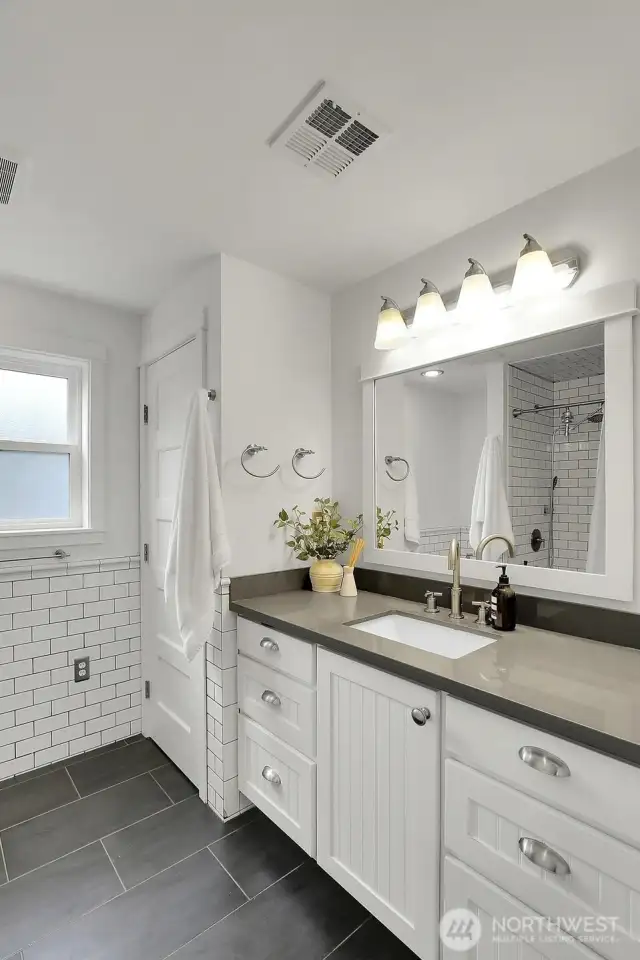 Half tiled wall and quartz counter tops in the primary bathroom.