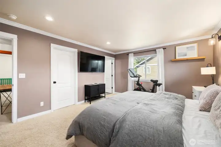 Looking across the primary bedroom with a king-sized bed, toward the walk-in closet and the primary bath.