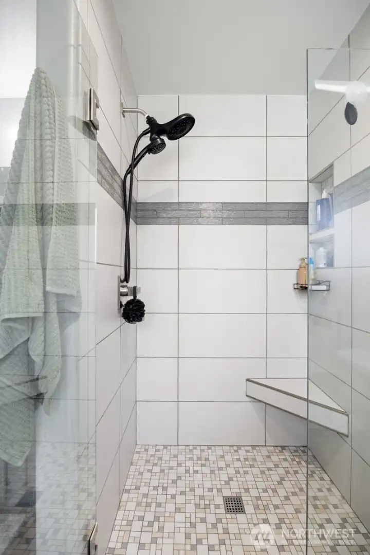 The tile shower is large and has a nice corner bench and a large niche above for products.