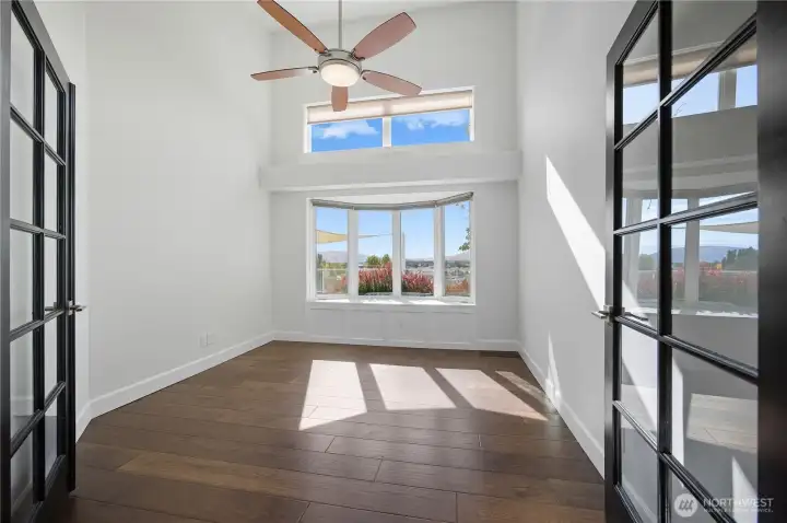 Office -   Bright and inspiring home office with French doors, vaulted ceilings, and large windows framing scenic views — ideal for remote work or a creative studio.