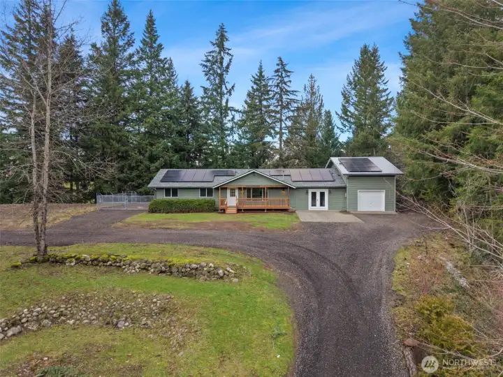 Large gravel driveway with parking pad and additional attached garage with mezzanine space above.