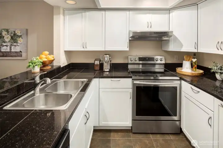Freshly updated kitchen with a newer stainless steel appliance package and sink.  Granite tile counters. And the fan above the stove is a hummer!