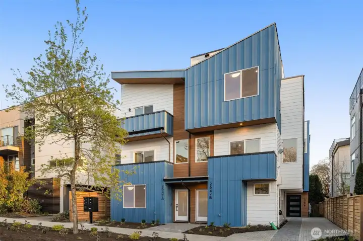 Welcome home, a striking contemporary residence, featuring deep navy siding and warm wood accents built by Intracorp.
