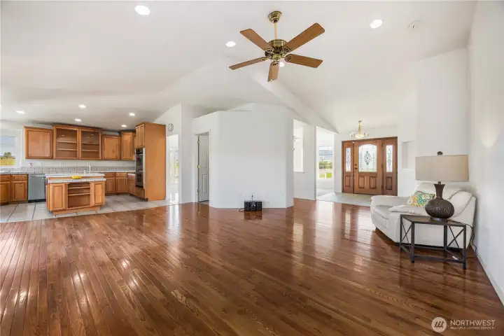 Spacious family room with vaulted ceilings, stunning hardwood floors, and abundant natural light creating an open, airy feel