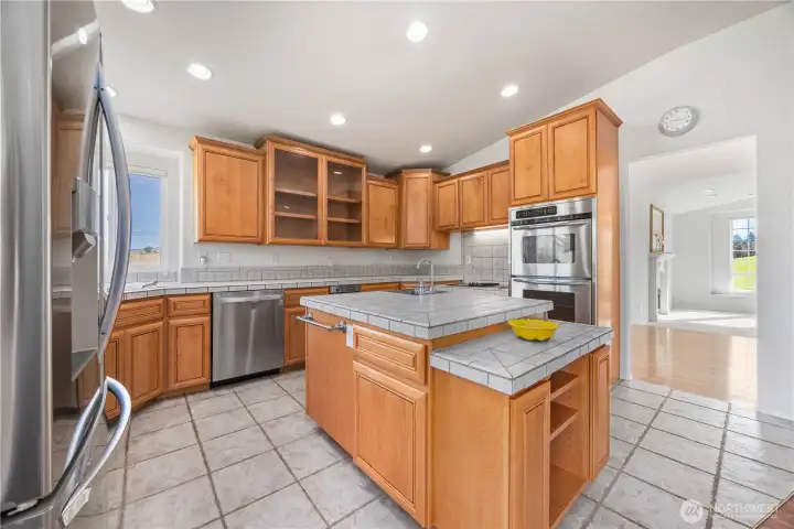 Well-appointed kitchen with stainless steel appliances, double ovens, tile countertops, garbage disposal, and large pantry for storage