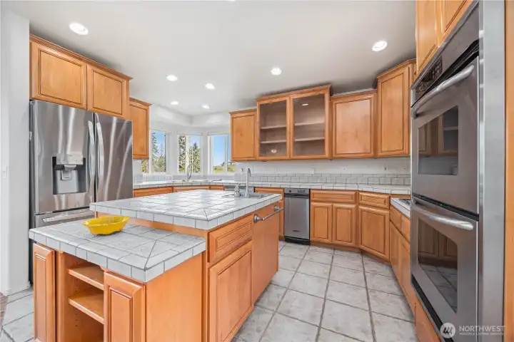 Well-appointed kitchen with stainless steel appliances, double ovens, tile countertops, garbage disposal, and large pantry for storage