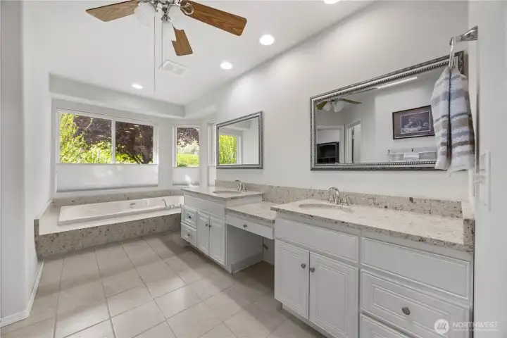Primary en suite featuring tub, tile step-in shower with glass door, double sinks, and functional layout