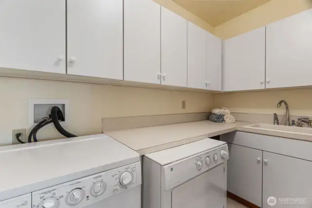 Lower level laundry room with utility sink and lots of cabinet and counter space for folding