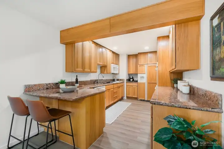 Expansive kitchen with solid wood cabinetry, granite counters, and breakfast bar seating.