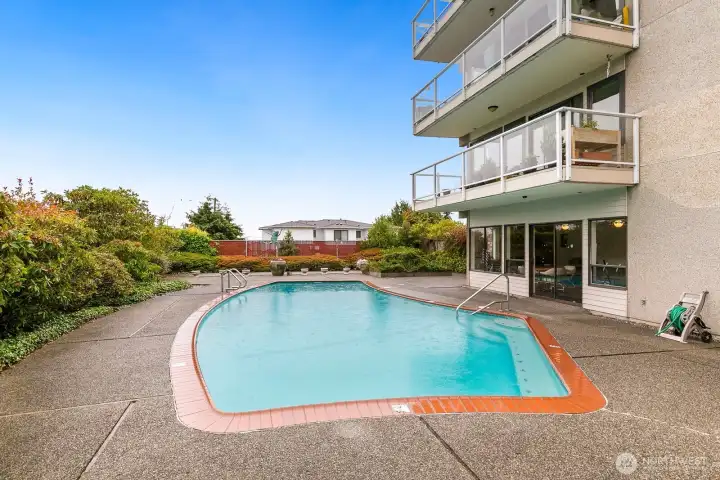 Heated outdoor pool surrounded by landscaped greenery and ocean air.