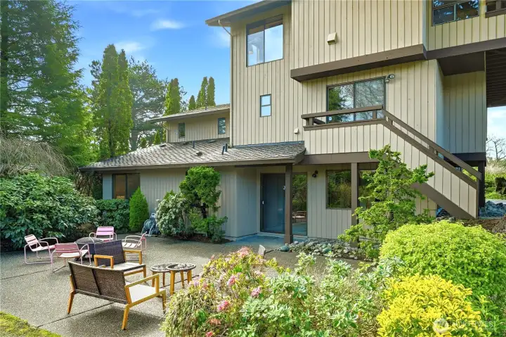 View of the rear of the house with large private patio with sliders from the lower level den