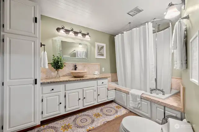 Main level full bath features plenty of custom cabinetry and an oversized jetted tub.