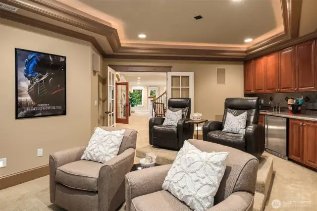 Media Room with kitchenette featuring custom cabinetry, granite counter, and stone backsplash