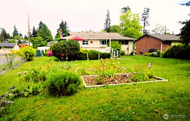 Large yard with trees, shrubs, and garden beds.