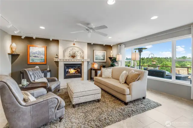 Living room features a custom design travertine gas fireplace surround, large picture windows with views of Mt. Rainer. Track lighting helps to display art work.