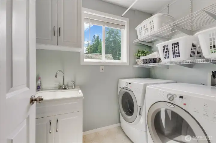 Laundry room is spacious and features front load washer and dryer that convey. Shelving & soaking sink with cabinet storage