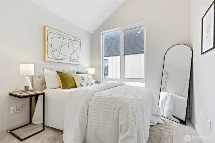 This dreamy bedroom is a sunlit retreat featuring vaulted ceilings, large windows, and just the right amount of personality.