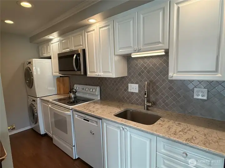 Light and bright kitchen. Pantry with pull out shelves opposite of the dishwasher.  Stackable washer and dryer at the end of the kitchen opposite the primary bedroom.