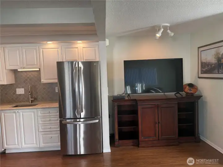 Kitchen with French doors and bottom freezer. TV and entertainment center directly across from the chairs across the living room.