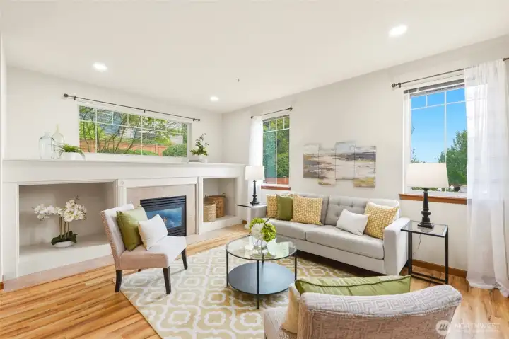 Bright, open-concept living room featuring a gas fireplace with a tile hearth and LVP flooring.