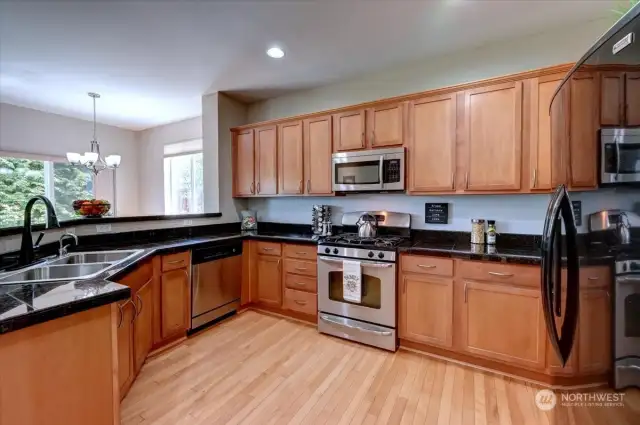 Beutifully keep kitchen with light cheey cabinets and gas stove.