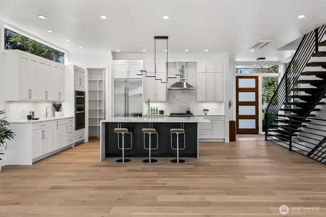 An entertainer’s kitchen with an edge.  The heart of 4015A centers around this striking chef’s kitchen, anchored by a charcoal-stained island and flanked by crisp white cabinetry and top-tier appliances. An oversized pantry and thoughtful lighting elevate both form and function, while the wide-plank oak flooring brings warmth to the modern palette.