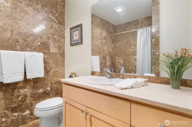 The Mainbath is conveniently located near the second bedroom and main living space, this full bathroom features rich marble tile, a sleek vanity, and a tub/shower combo
