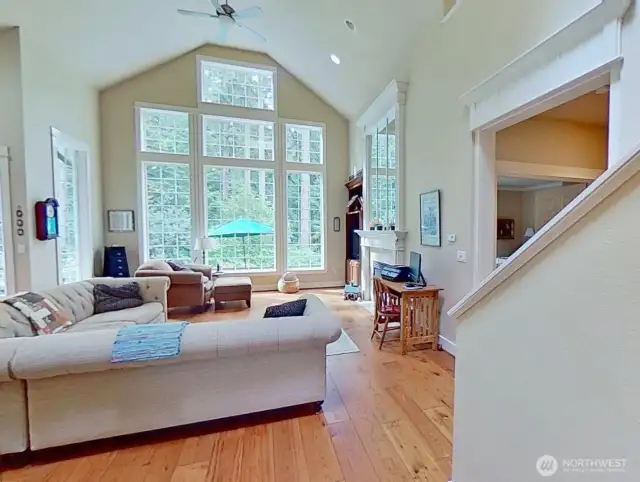 Living room features hardwood floors, vaulted ceiling, and a wall of windows.