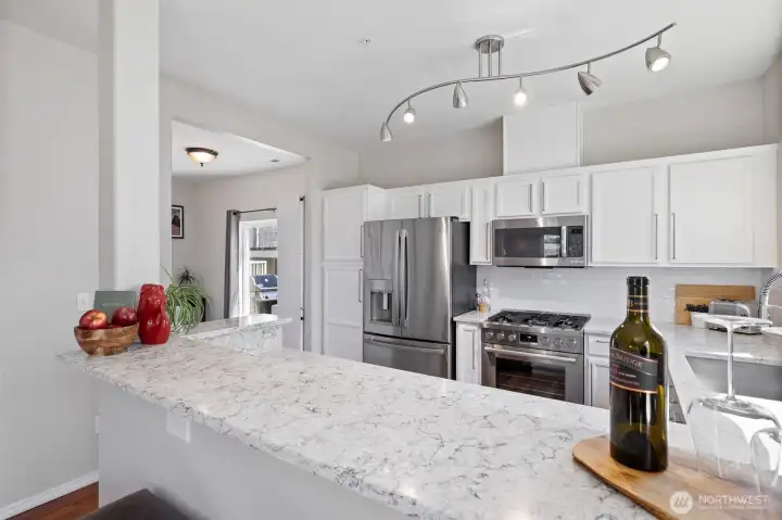 Eating bar with quartz countertop and new lighting and appliances in the backround
