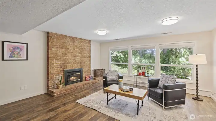 The lower level features a charming brick fireplace and abundant natural light from the wall of windows, offering an open, inviting space ready to be personalized with your own furniture and style.