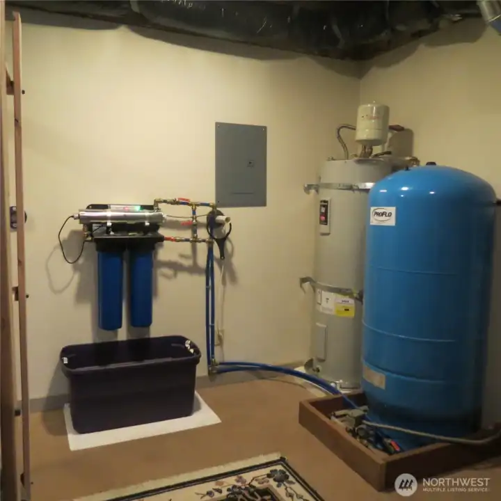 Utility room with new hot water heater and full-house water treatment system. Clean and tidy space with additional storage that is out of frame to the left.