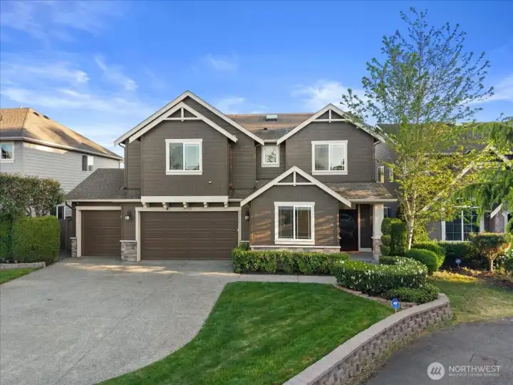 Striking two-story exterior with attractive architectural detailing, a three-car garage, and a wide driveway. Professionally landscaped front yard with manicured lawn and welcoming curb appeal.