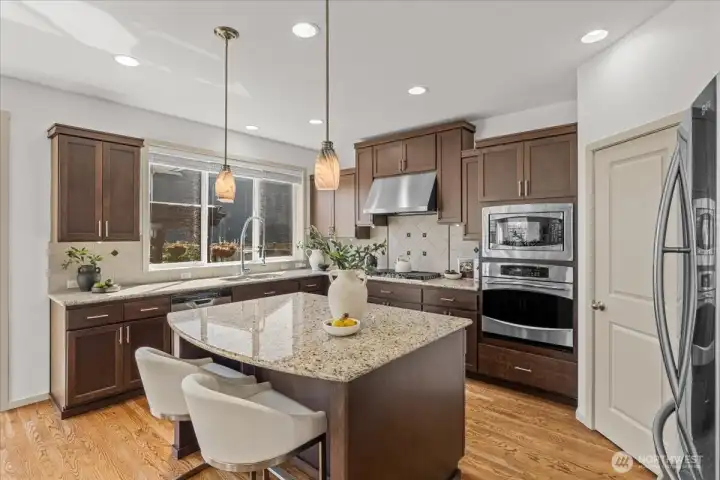 Well-appointed kitchen featuring rich wood cabinetry, granite countertops, stainless steel appliances, and a center island with seating.