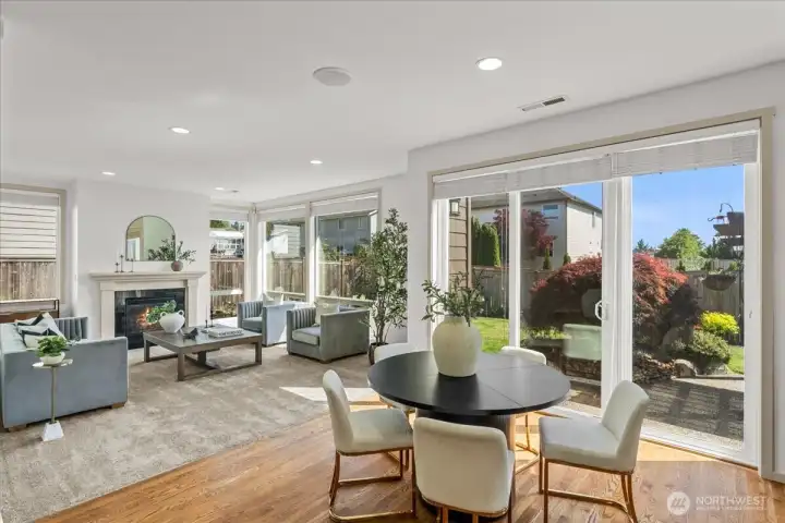 Sunny dining nook overlooks the backyard through large windows and sliding glass doors. The adjacent family room offers a cozy fireplace and generous natural light.