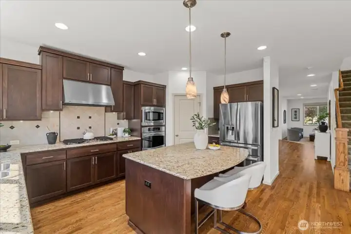 Spacious chef’s kitchen featuring granite countertops, extensive cabinetry, stainless steel appliances, and a large center island with bar seating. Open design offers a seamless connection to the main living areas.