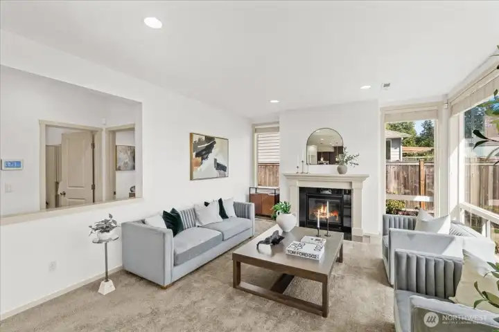 Comfortable gathering space with a gas fireplace, oversized windows, and abundant natural light. An open-concept layout creates an ideal setting for relaxing or entertaining.