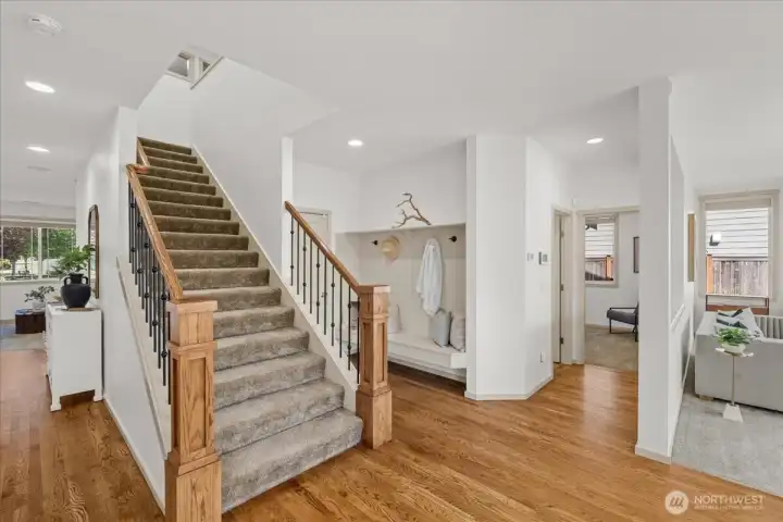 Open stairway with wood accents, hardwood flooring, and a built-in bench area. Thoughtful design creates an organized transition between living spaces.